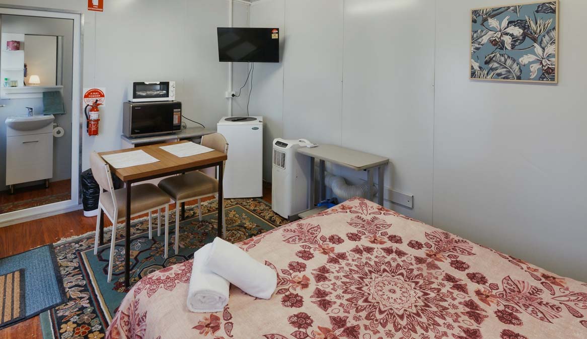 Bed, Table, TV available in one room of cabin accommodation